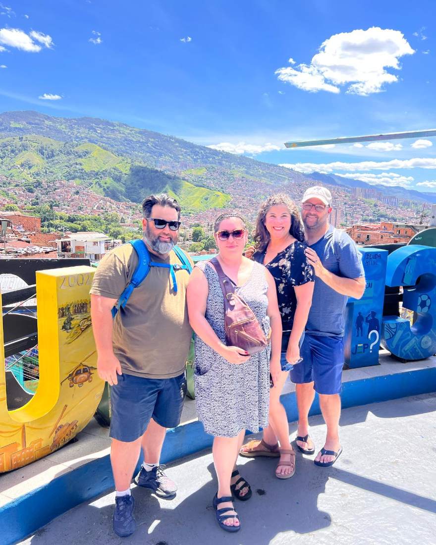 Viajeros en el letrero de la Comuna 13 con Medellín al fondo